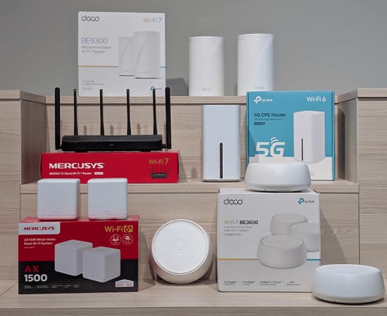 Flera mesh-routrar och Wi-Fi-system från TP-Link och Mercusys, inklusive modeller med Wi-Fi 6 och Wi-Fi 7, uppställda på träpodium.